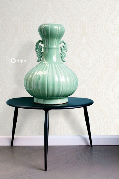 Dekorative Vase auf einem Beistelltisch vor einer gemusterten Wand