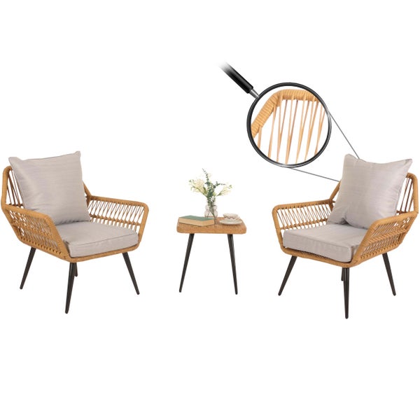 Zwei Rattansessel mit grauen Kissen und ein Rattantisch mit Blumen und Buch