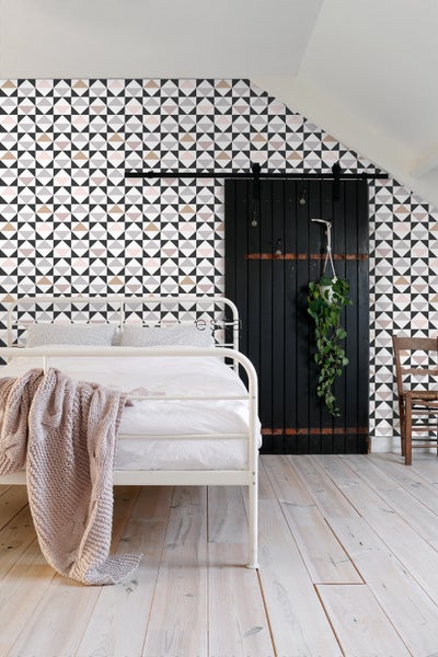 Schlafzimmer mit geometrischer Tapete, weißem Bett und schwarzer Schiebetür