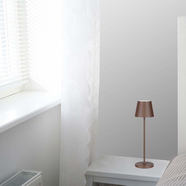 Dekorative Tischleuchte auf einem Nachttisch in einem hellen Raum.