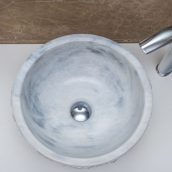 Rundes Aufsatzwaschbecken aus Marmor mit Armatur in der Draufsicht.