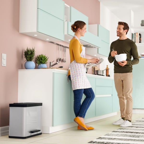 Helles Küchendesign mit Paar, Spülbecken, Küchenutensilien und Treteimer