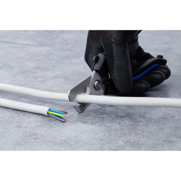 Eine Hand in einem schwarzen Handschuh schneidet ein weißes Elektrokabel mit einer Kabelschere.