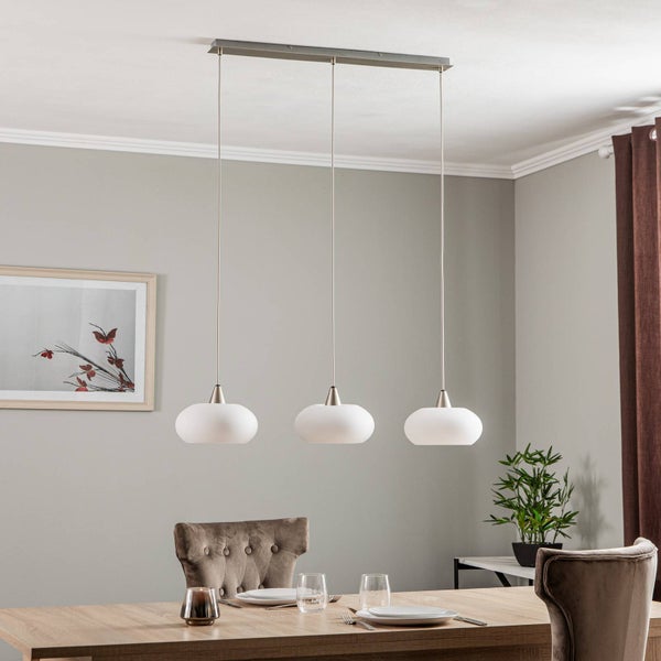 Dreiflammige Pendelleuchte mit ovalen Glasschirmen über einem Esstisch aus Holz in einem modern eingerichteten Esszimmer.