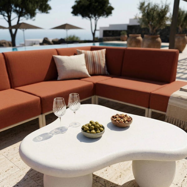 Moderne Garten-Lounge mit orangefarbenem Ecksofa und weißem, organisch geformtem Couchtisch auf einer Terrasse am Pool.