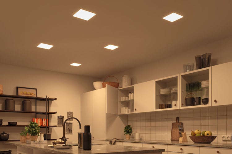 Helle, organisierte Küche mit fünf quadratischen LED-Deckenpaneelen, weißen Schränken, Stein-Arbeitsplatte und modernem Design.