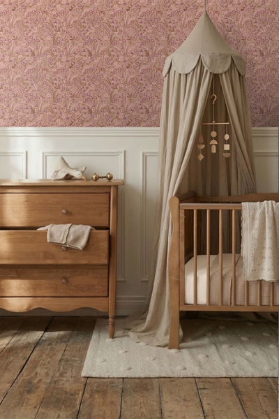 Vliestapete mit floralem Waldtier-Muster in einem Kinderzimmer über weißen Wandpaneelen und einer Holzkommode mit Weidenkorb.