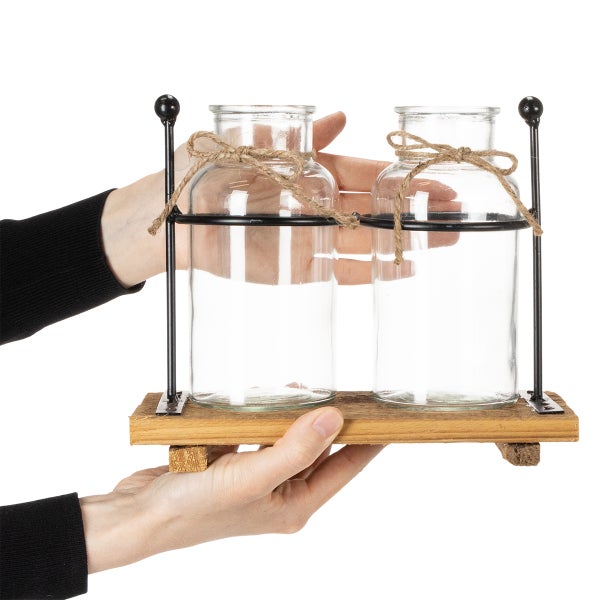 Zwei dekorative Glasflaschen in einem Holzständer mit Metallgestell und Juteband.