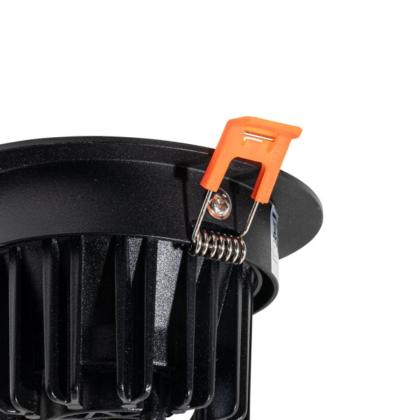 Detailaufnahme eines schwarzen LED-Einbaustrahlers mit Kühlrippen und einer orangefarbenen Montagefeder.