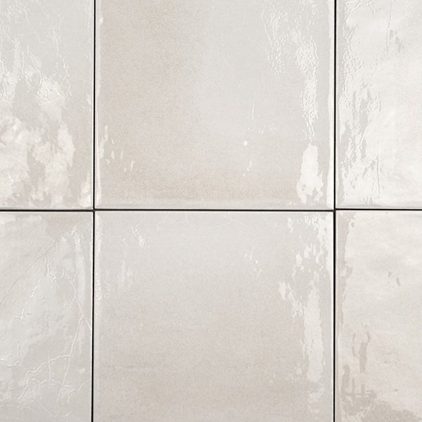 Quadratische Wandfliesen mit glänzender, leicht unebener Oberfläche in neutralem Ton
