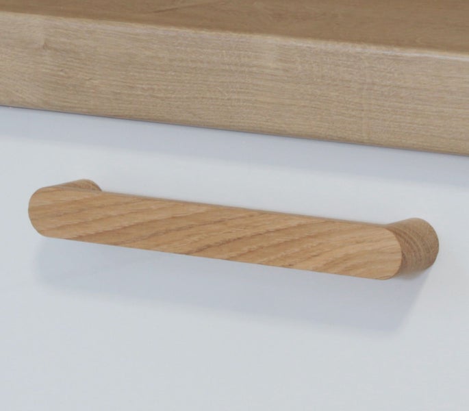 Möbelgriff in Holzoptik an einer weißen Schubladenfront