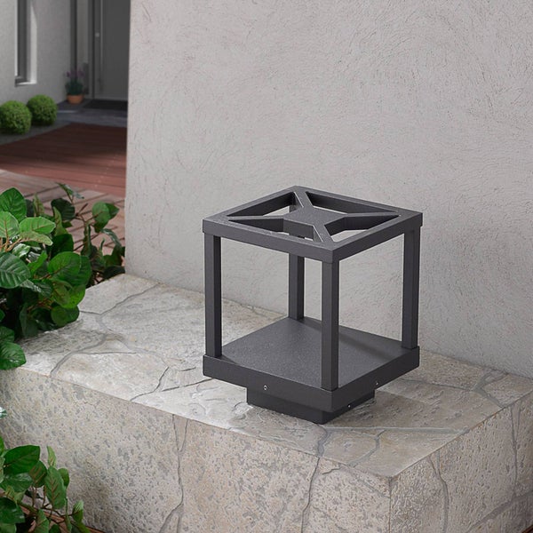 Würfelförmige Außen-Sockelleuchte in Anthrazit auf einer Natursteinmauer im Gartenbereich.