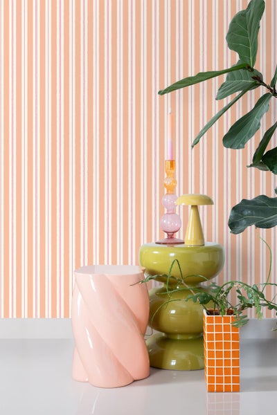 Innenraum mit gestreifter Tapete, Beistelltisch, Lampe, Kerzenständer und Pflanze für eine moderne Raumgestaltung.