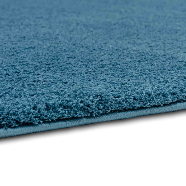 Nahaufnahme eines blauen Hochflorteppichs mit gekettelter Kante.