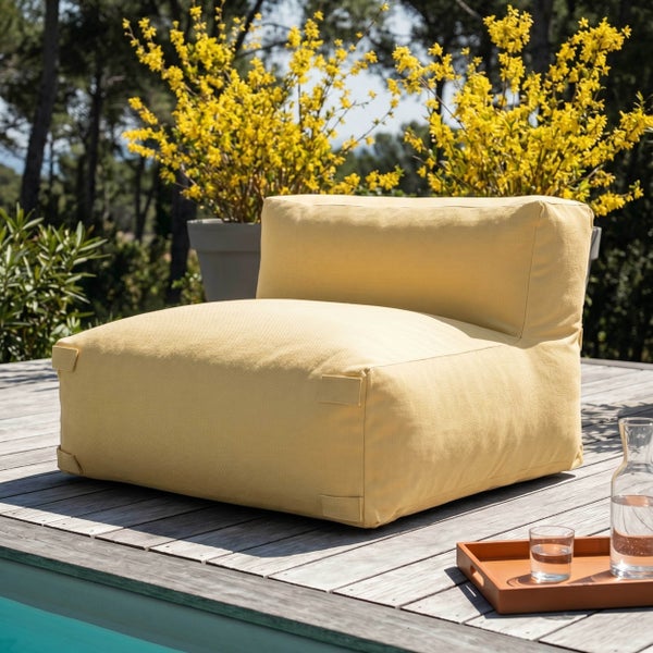 Moderner gelber Outdoor Sessel auf einer Holzterrasse am Pool mit gelb blühenden Sträuchern im Hintergrund.