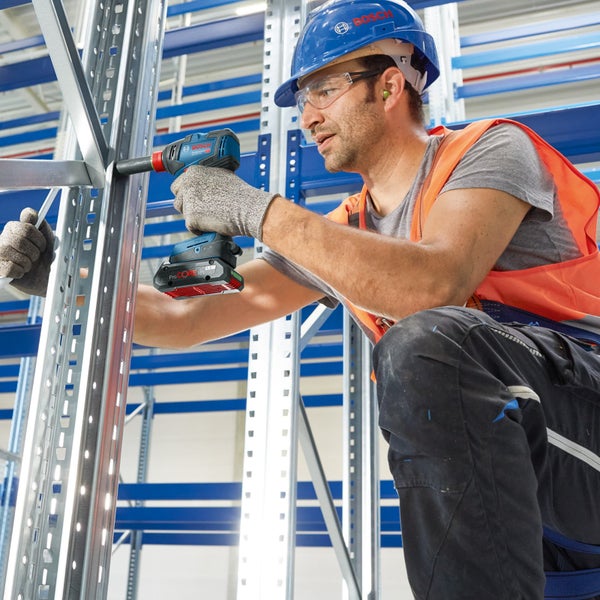 Ein Handwerker befestigt ein Metallregal mit einem Akku-Schlagschrauber von Bosch.