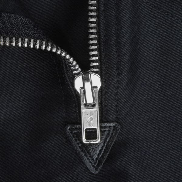Nahaufnahme eines Metallreißverschlusses an dunklem Stoff mit JOB Logo auf dem Schieber.