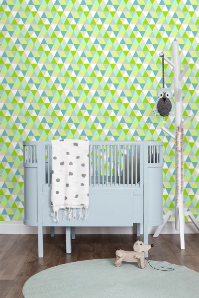 Kinderzimmer mit blauem Gitterbett, Spieluhr, Holzspielzeug und Tapete mit geometrischem Muster