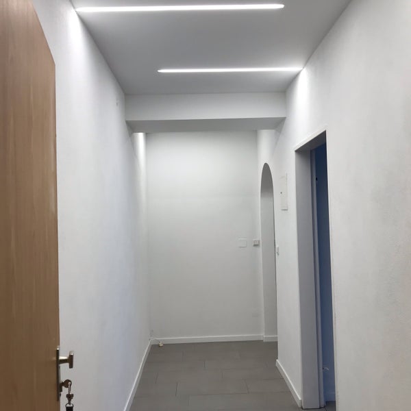 Flur mit weißen Wänden und linearen Deckenleuchten