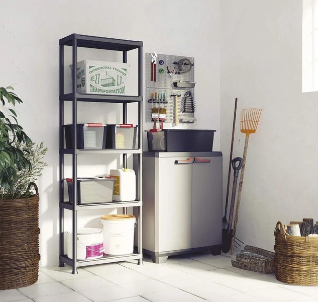 Organisiertes Lagersystem in einer hellen Werkstatt mit einem dunklen Kunststoffregal, einem grauen Schrank und einer Werkzeugwand.