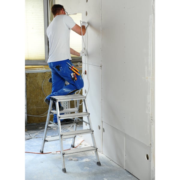Handwerker auf einer Trittleiter bei Elektroinstallationen an einer Gipskartonwand