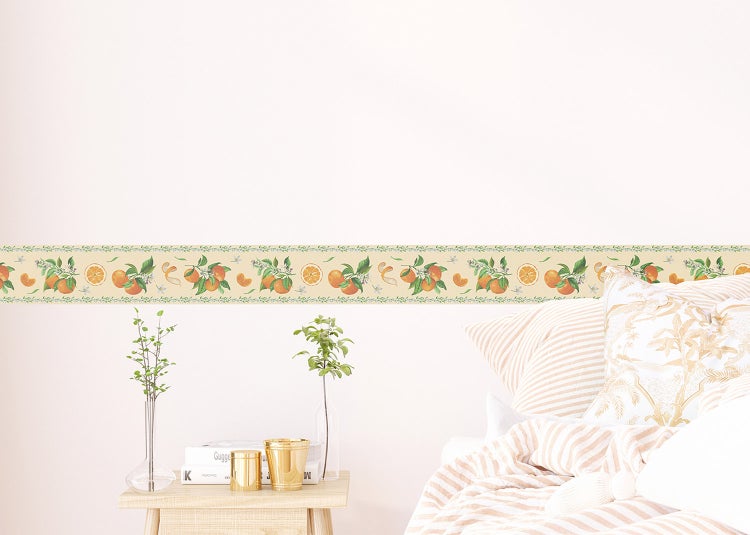 Wandbordüre mit Orangen- und Blättermotiv in einem hell gestalteten Schlafzimmer über einem Bett und Beistelltisch.