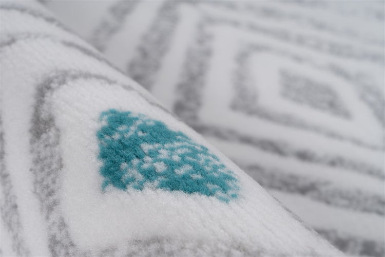 Detailansicht eines Teppichs mit geometrischem Muster aus weichem Flor.