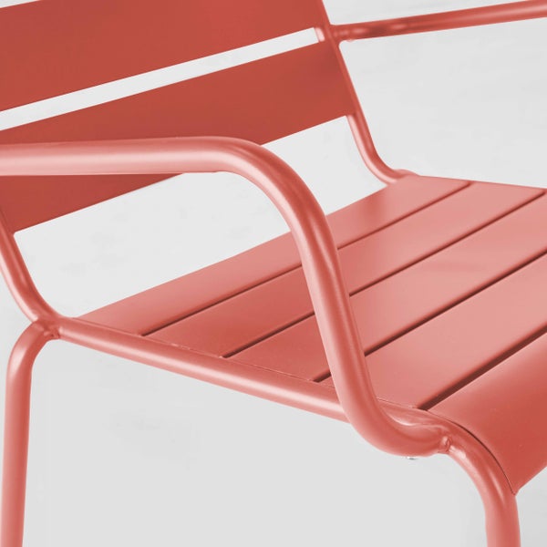 Nahaufnahme eines roten Metall-Gartenstuhls mit Sitzfläche aus Lamellen und geschwungenen Armlehnen.