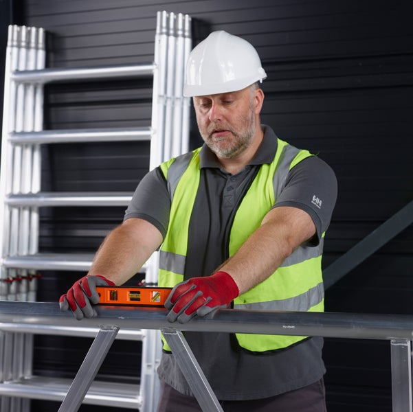 Handwerker prüft Gerüst mit Wasserwaage