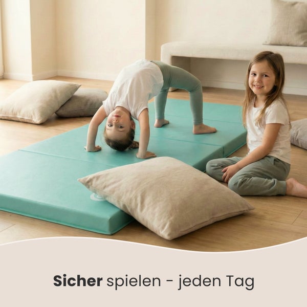 Zwei Mädchen spielen auf einer Turnmatte mit Kissen