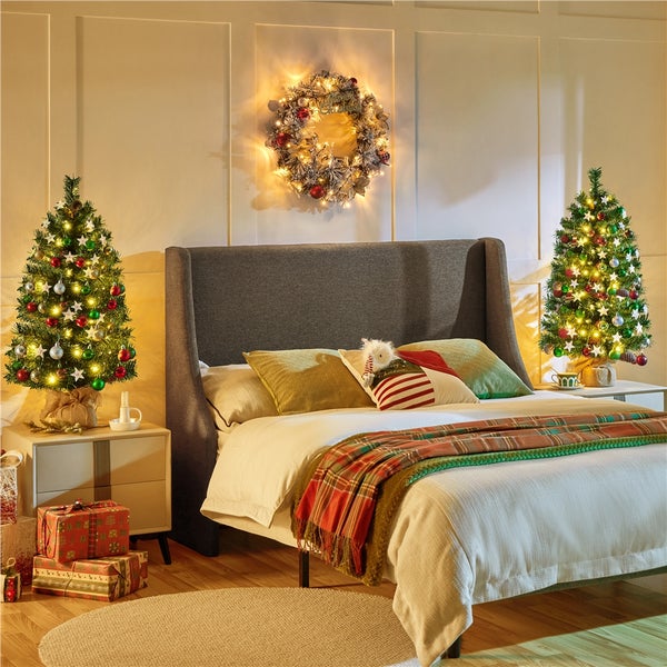 Dekoriertes Schlafzimmer mit Weihnachtsbäumen, Kranz und Geschenken für eine festliche Atmosphäre