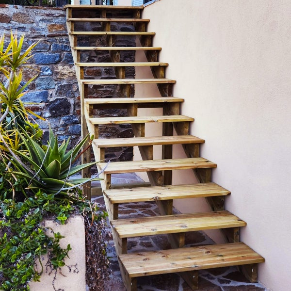 Holztreppe im Außenbereich mit Natursteinmauer und Pflanzen