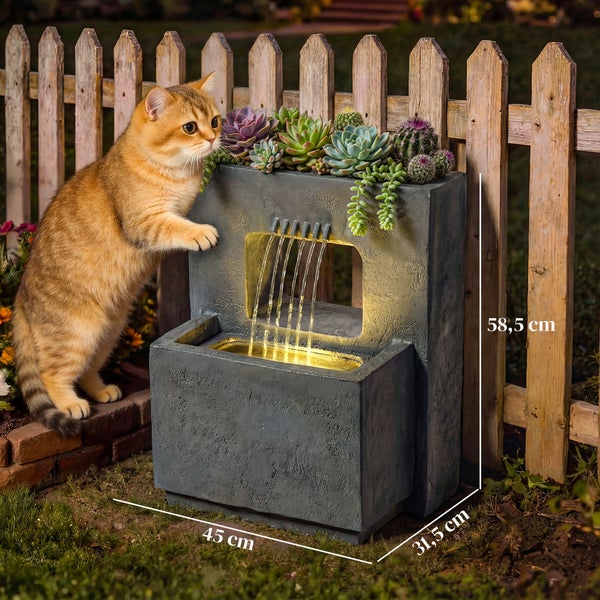 Moderner Gartenbrunnen in Steinoptik mit Beleuchtung und Pflanzbereich, Maße 58,5 mal 45 mal 31,5 Zentimeter, in Gartenszene mit Katze.