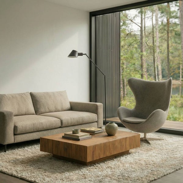 Wohnzimmer mit Sofa, Sessel, Couchtisch, Stehlampe und Teppich vor Fenster