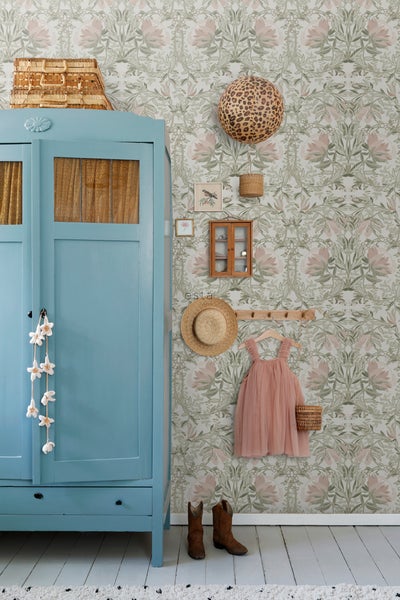 Dekorative Inneneinrichtung mit floraler Tapete, blauem Schrank und diversen Wohnaccessoires