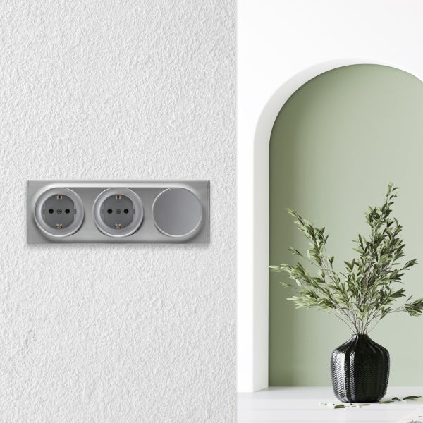 Dreifach Steckdosenkombination in modernem Design an einer Wand montiert mit einer Vase und Pflanze im Hintergrund.