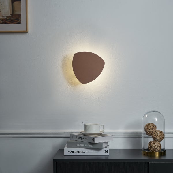 Dreieckige Wandleuchte beleuchtet die Wand im Raum.