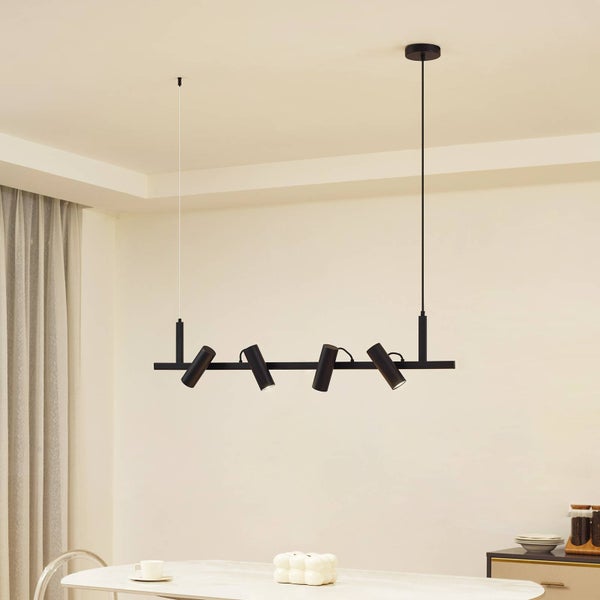 Schwarze Hängelampe mit vier Strahlern über einem Esstisch.