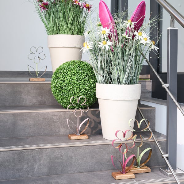 Dekorative Blumentöpfe mit Kunstblumen und Dekofiguren auf einer Treppe