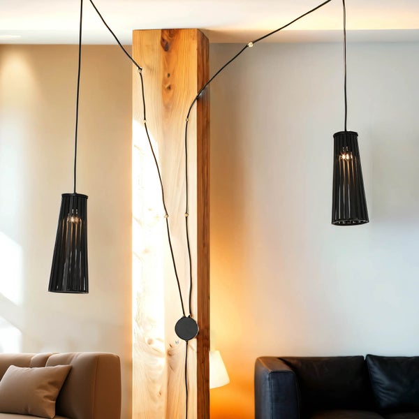 Zwei schwarze Pendelleuchten hängen in einem Wohnzimmer.