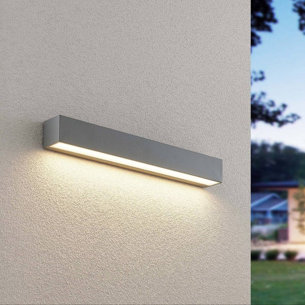 Rechteckige LED Außenwandleuchte aus Metall, montiert an einer Hauswand, strahlt warmweißes Licht nach unten ab.