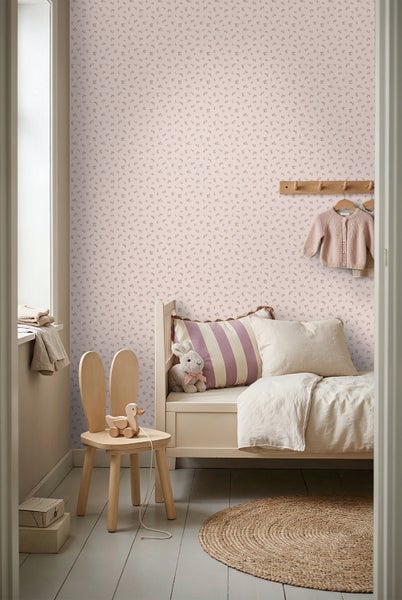 Helles Kinderzimmer mit kleingemusterter Tapete, Holzbett, Stuhl mit Hasenohren und rundem Jute-Teppich im skandinavischen Stil.