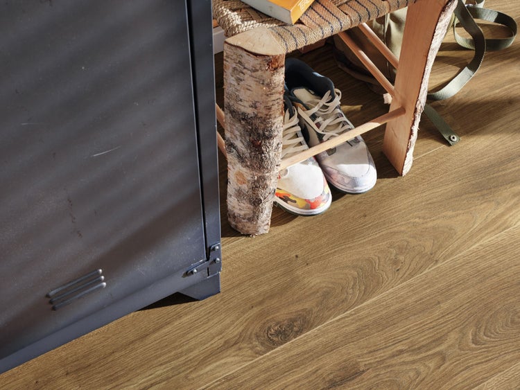 Holzoptik Laminatboden in einem modern eingerichteten Raum mit einem Metallschrank und einem Hocker aus Birkenholzstämmen.
