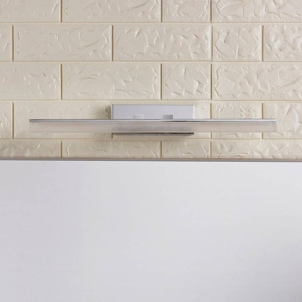 Schlanke, rechteckige LED-Badezimmer-Spiegelleuchte in Chrom-Optik, montiert an einer Wand mit Steinoptik.