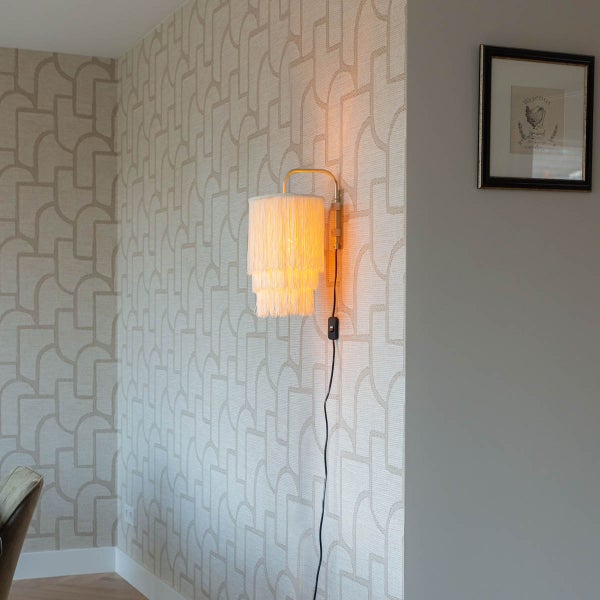 Wandleuchte mit Fransen an einer Wand mit geometrischem Muster