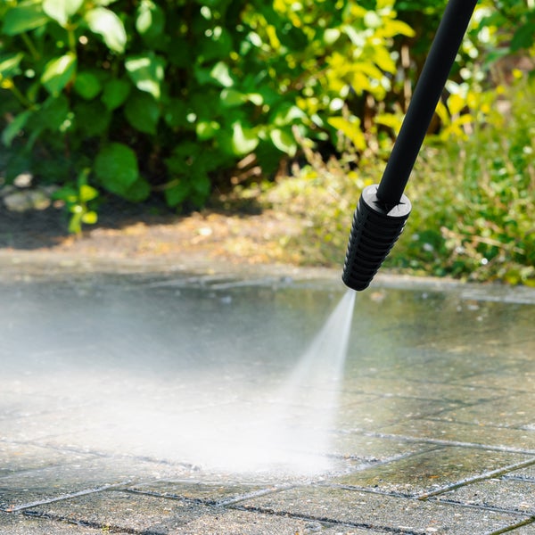 Hochdruckreiniger im Einsatz zum Reinigen einer Steinoberfläche im Freien