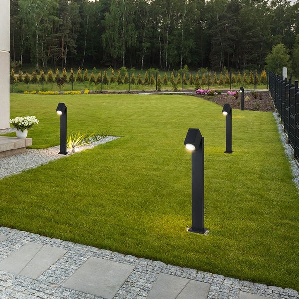 Gartenlandschaft mit Rasen und mehreren Außenleuchten.