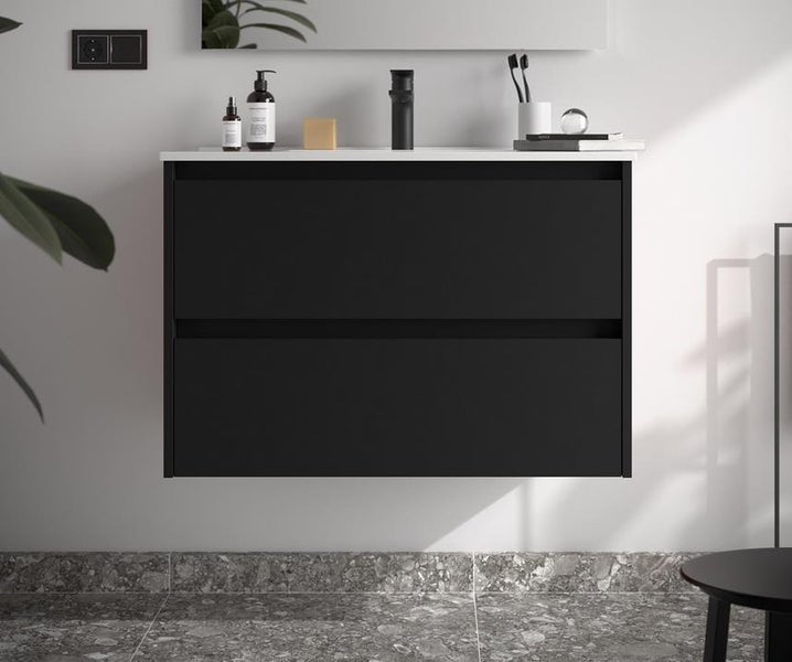 Wandhängender Waschtischunterschrank mit zwei matt schwarzen Schubladen, weißer Waschtischplatte und schwarzer Armatur in modernem Bad.
