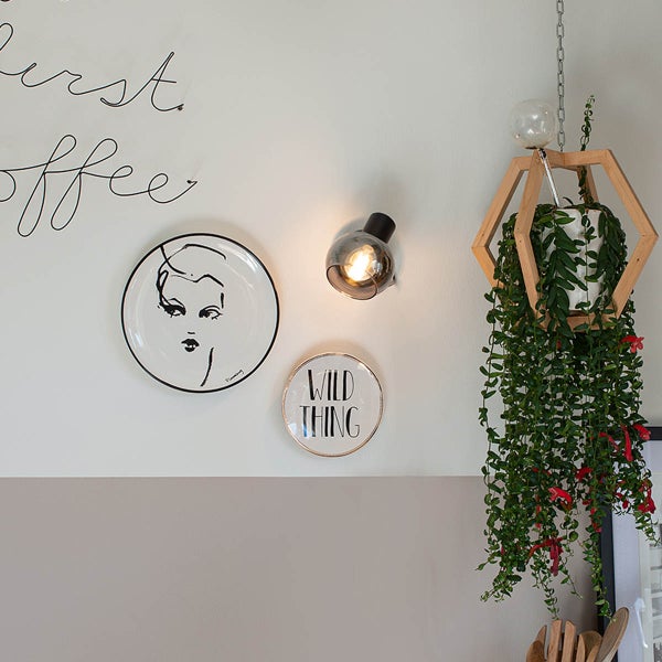 Wanddekoration mit Teller, Wandleuchte und hängender Zimmerpflanze in Holzhalterung