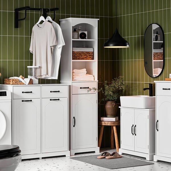 Badezimmer mit weißen Möbeln, Waschbecken, Spiegel und Wäscheständer vor grünen Fliesen